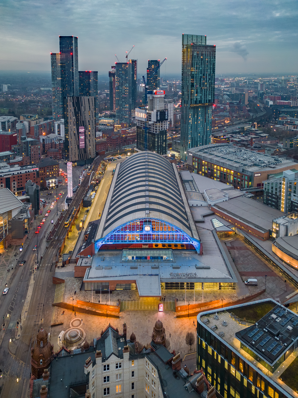 An daytime aerial drone shot showing a birds eye view of Manchester Central and the surrounding skyscrapers and city.