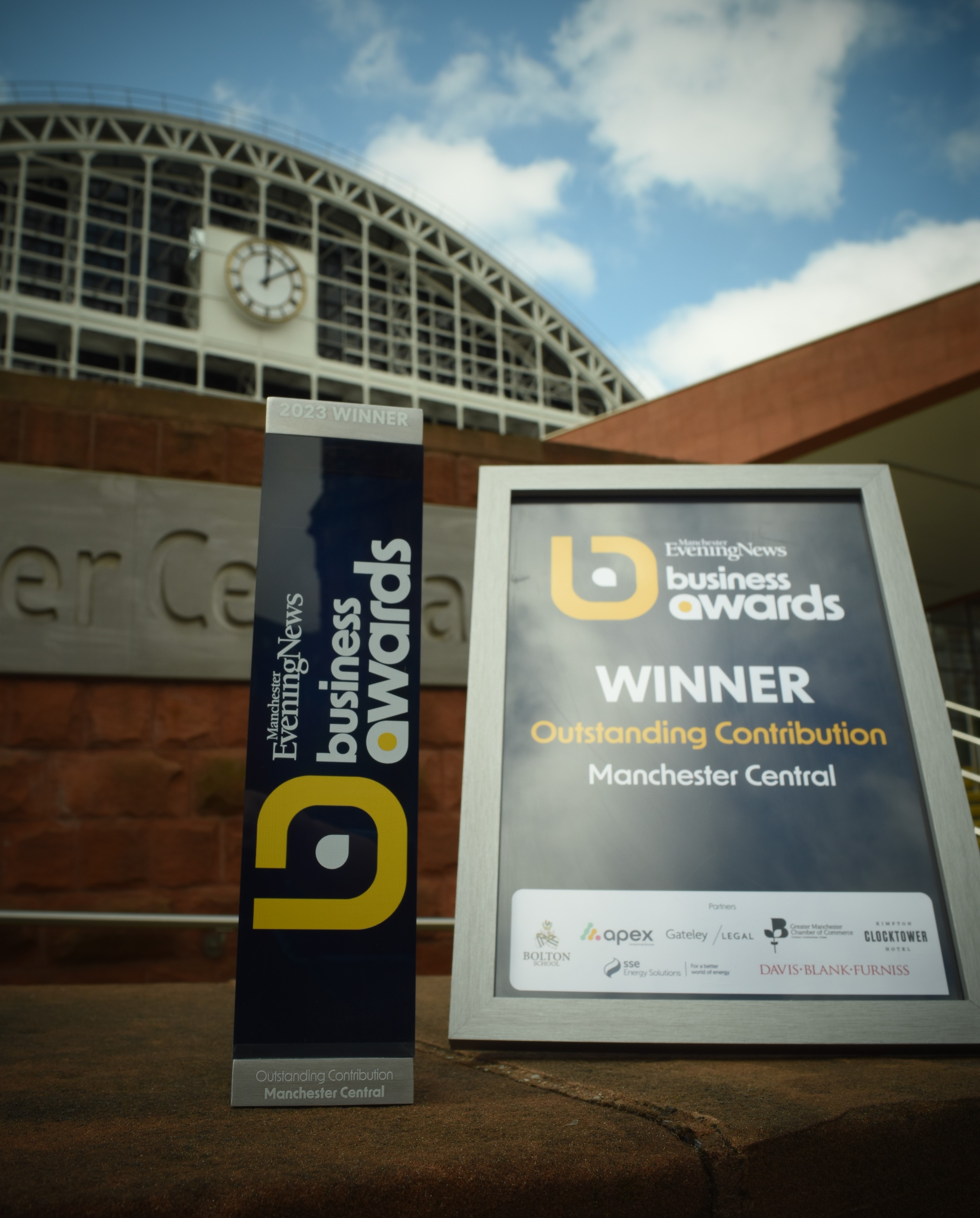 MEN Business Awards certificate and award sat in front of the exterior Manchester Central